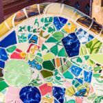 Primer plano de una colorida pared de mosaico con varios azulejos de forma irregular con dibujos verdes, azules, amarillos y rojos.