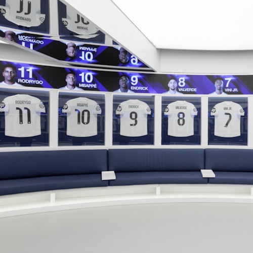 A modern locker room with football jerseys displayed in glass cases, names and numbers above, and a circular seating area.