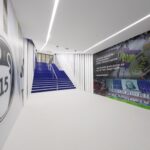 A modern hallway with white walls, a blue staircase, and walls adorned with sports-related murals and text.